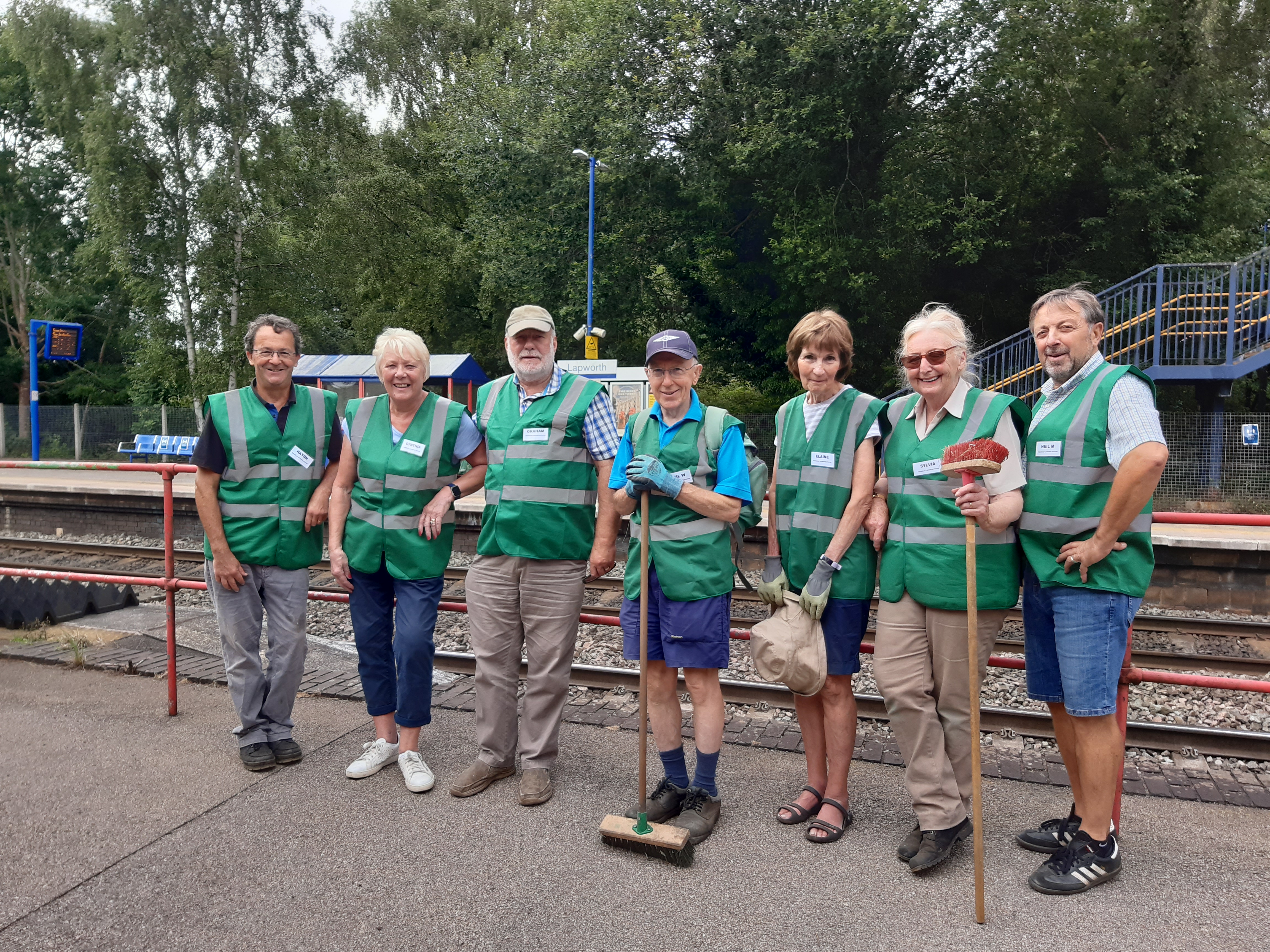 7 male and female station adopters with green high-vis vests at Lapworth Station.